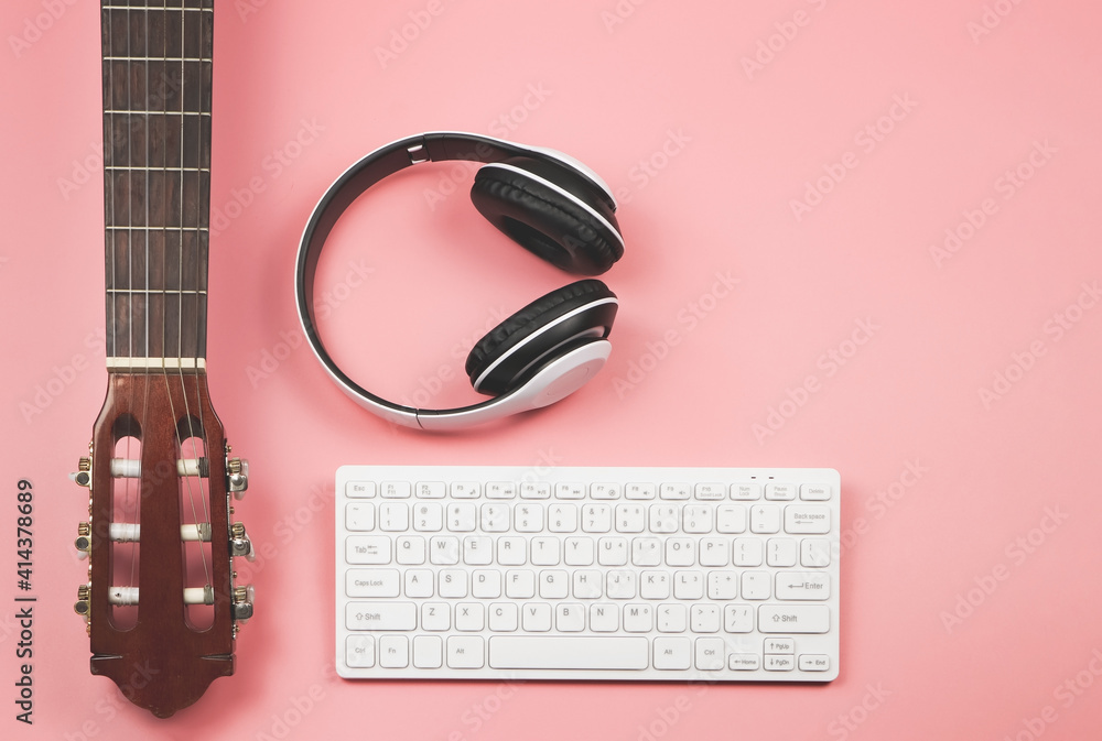 computer keyboard, headphones and acoustic guitar on pink background with copy space. Musician, leisure and online music learning concept. computer keyboard, headphones and acoustic guitar on pink background with copy space. Musician, leisure and online music learning concept.