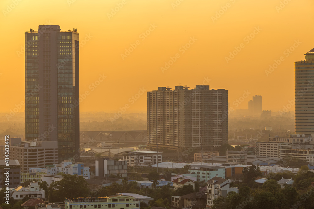 Fototapeta premium The blurred abstract background of the morning sun exposure to the tiny dust particles that surround the tall buildings in the capital, the long-term health issue of pollution