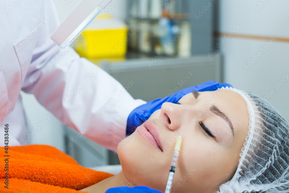 Naklejka premium Portrait of doctor using injection in beauty procedures to adult woman client