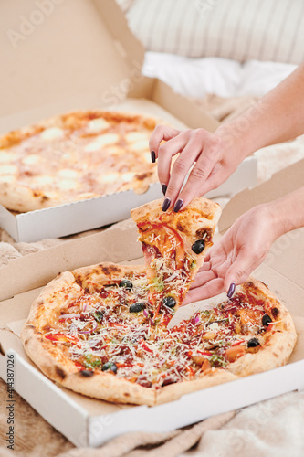 Pizza home delivery. Girl takes a piece pizza from the box. Weekend. Close-up
