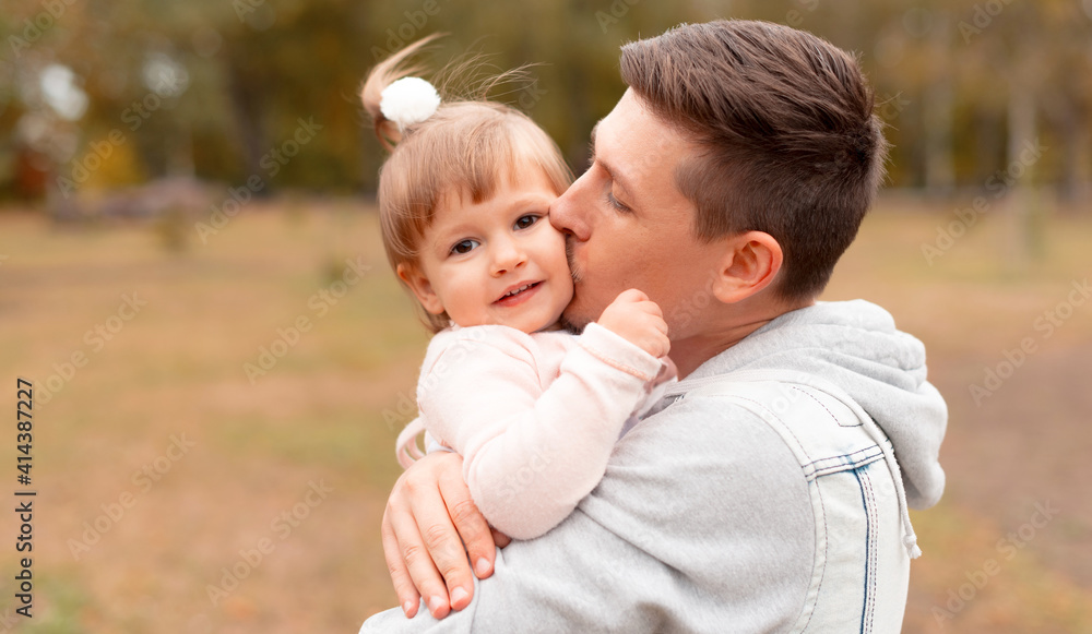 Cheerful young father kissing his little cute daughter outdoor. Cheerful young father kissing his little cute daughter outdoor.