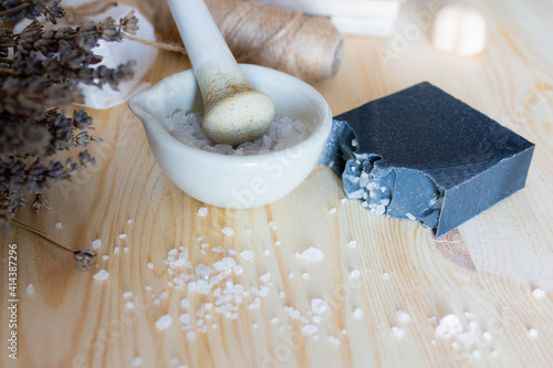 Eco flat lay with organic cosmetics, soap and shampoo, eco natural ingredients and lavender lying on wooden table, spa products, woman holding in hands salt pounder