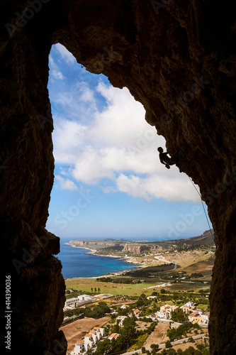 silhouette of a climber in a cave with the coast of San Vito lo Capo in Sicily