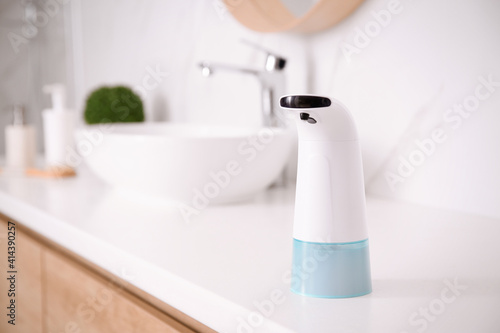 Fototapeta Naklejka Na Ścianę i Meble -  Modern automatic soap dispenser on countertop in bathroom. Space for text