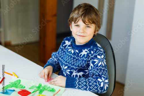 Little kid boy making paper origami tulip flowers for a postcard for mother's day or birthday. Cute child of elementary class school doing handicraft