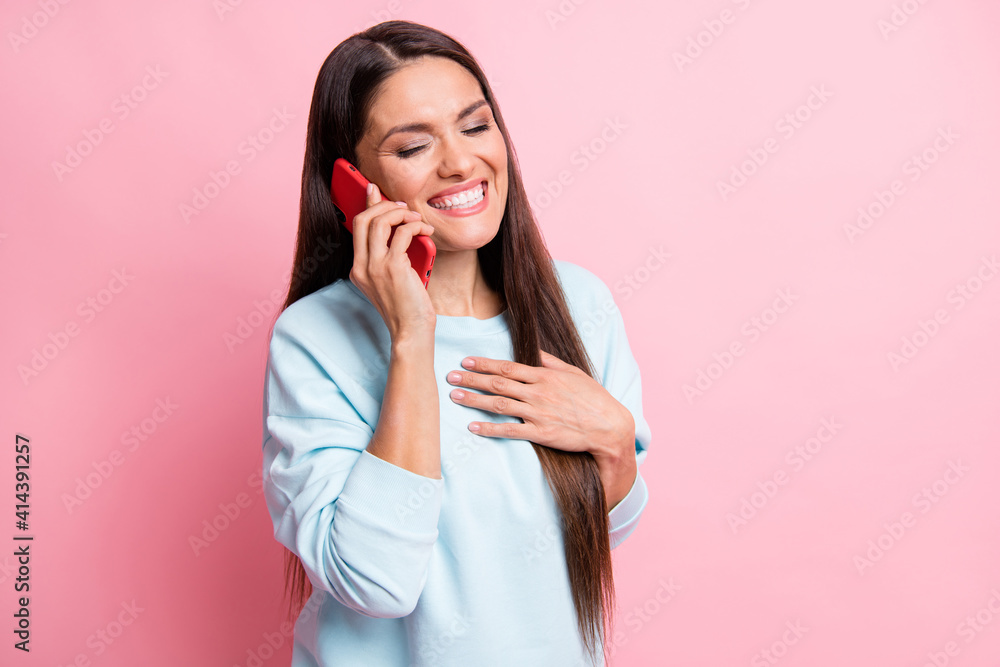 Photo portrait of brunette speaking on cellphone laughing hand on chest isolated on pastel pink color background Photo portrait of brunette speaking on cellphone laughing hand on chest isolated on pastel pink color background