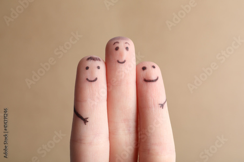Three fingers with drawings of happy faces on brown background