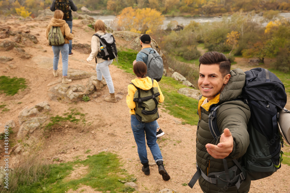 Group of hikers with backpacks climbing up mountains