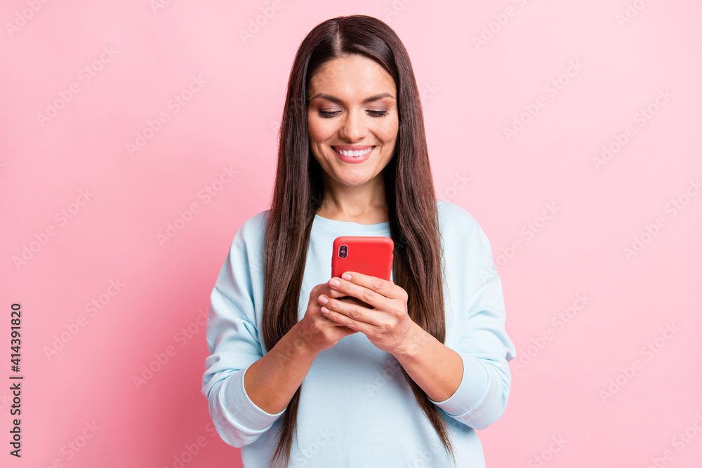 Photo of adorable sweet mature woman wear blue pullover typing modern gadget isolated pink color background Photo of adorable sweet mature woman wear blue pullover typing modern gadget isolated pink color background