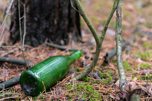 The green glass bottle lies thrown away in the forest and does not decompose