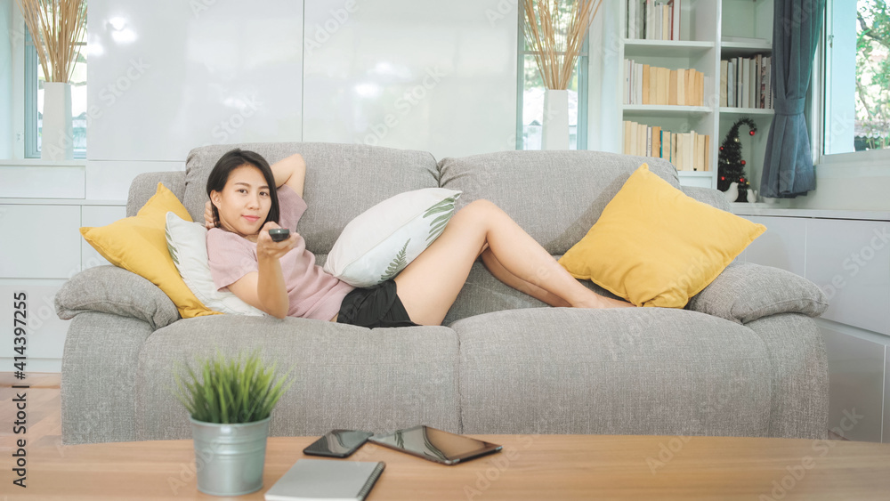 Young Asian teenager woman watching TV at home, female feeling happy lying on sofa in living room. Lifestyle woman relax in morning at home concept. Young Asian teenager woman watching TV at home, female feeling happy lying on sofa in living room. Lifestyle woman relax in morning at home concept.