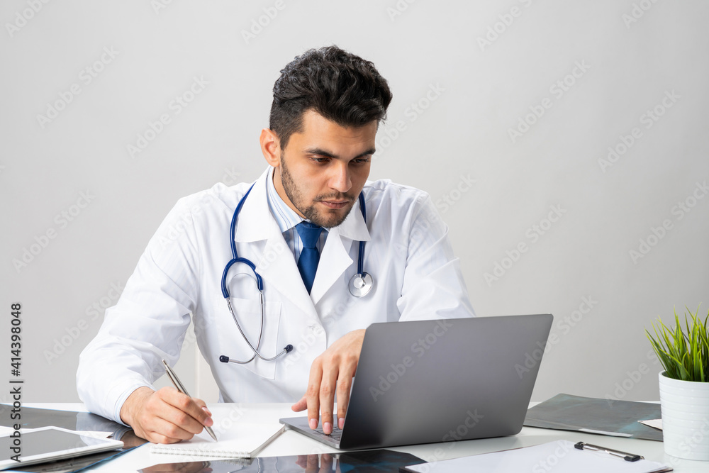 Handsome doctor sitting at desk in office Handsome doctor sitting at desk in office