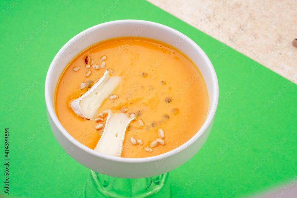 Pumpkin soup with eringi mushrooms in white plate on green background. Close-up. Top view. Space for text. Photo for cutting, for menu Pumpkin soup with eringi mushrooms in white plate on green background. Close-up. Top view. Space for text. Photo for cutting, for menu