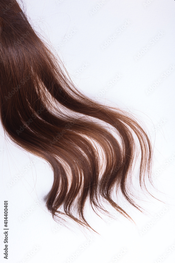 Naklejka premium a lock of natural brunette hair on a white background