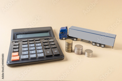 Calculator, mock-up of tractor-trailer, coins placed on light background. Concept. Tariffs, calculation, freight transport costs by truck.