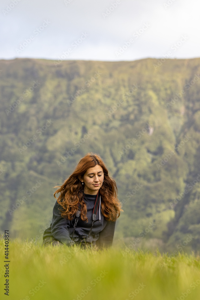 Girl sitting in grass, by Sete Cidades lake, enjoying the landscape, peacefully. Girl sitting in grass, by Sete Cidades lake, enjoying the landscape, peacefully.