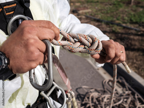 Concept: vertical work. Detail of hands making an eight knot in the safety rope.