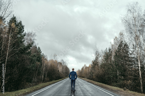 A businessman in a business suit stands on the road, a long way in front. Development concept, start-up, investment search.