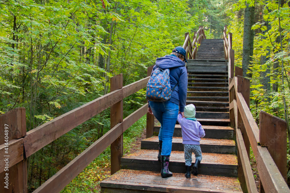 Mother and daughter are traveling. Mother and daughter are walking along the path of the nature reserve in the forest. Mother and daughter are traveling. Mother and daughter are walking along the path of the nature reserve in the forest.