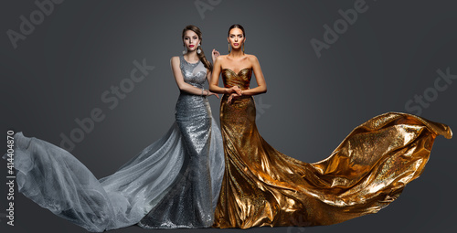 Fototapeta Fashionable two Woman in Golden Evening Dress and Silver Gown