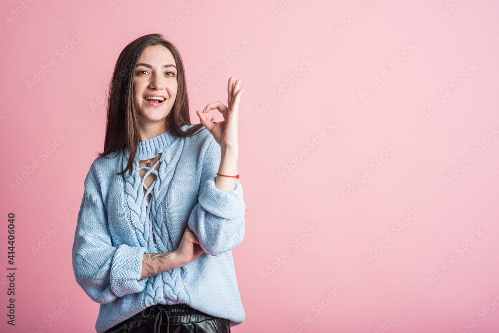 Brunette girl in studio on pink background shows hand okay gesture with copyspace Brunette girl in studio on pink background shows hand okay gesture with copyspace