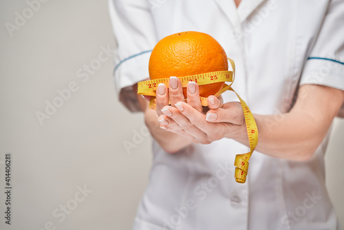 nutritionist doctor healthy lifestyle concept - holding orange fruit and measure tape