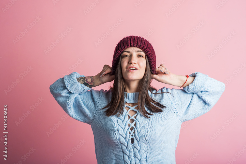Portrait of a brunette girl in a warm hat in the studio on a pink background Portrait of a brunette girl in a warm hat in the studio on a pink background