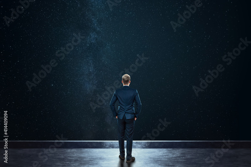 Rear view businessman stands against the background of the starry sky. Mixed media. Concept Dream, success, opportunity, development.
