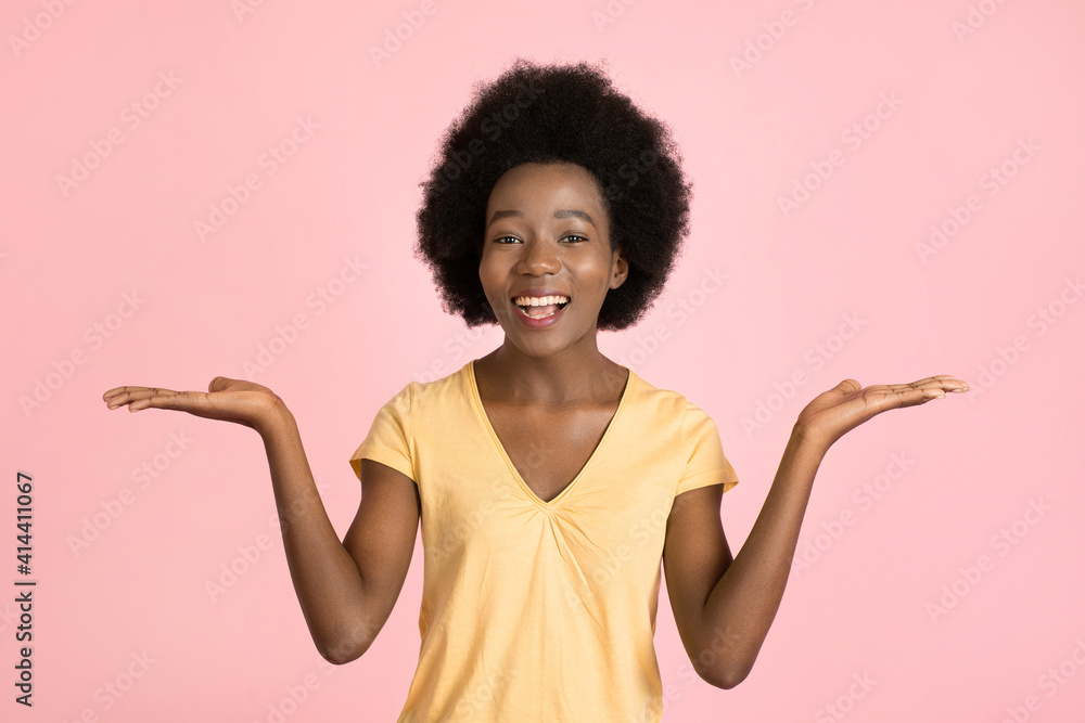 What is better, what to choose. Young happy surprised African woman with afro hair, promoting smth and showing two options with hands, on pink background What is better, what to choose. Young happy surprised African woman with afro hair, promoting smth and showing two options with hands, on pink background