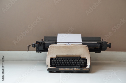 front view antique cream and black typewriter on marble floor, brown wall background, technology, object, vintage, retro, copy space