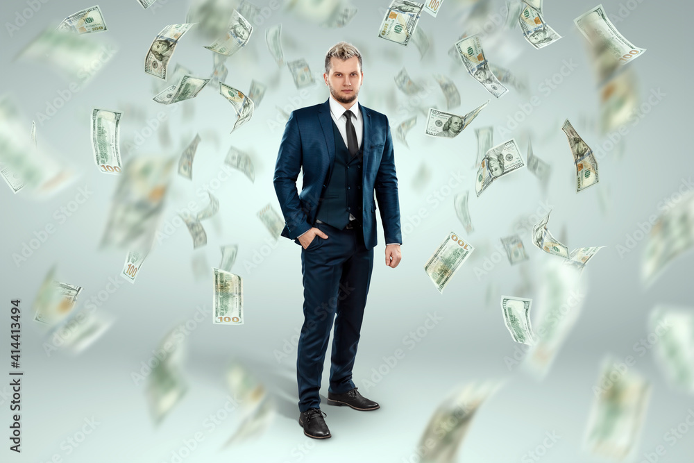 A man in a business suit stands against the background of falling dollars, banknotes are falling from the sky. Business concept, bookmaker, sports betting, investment, passive income. A man in a business suit stands against the background of falling dollars, banknotes are falling from the sky. Business concept, bookmaker, sports betting, investment, passive income.