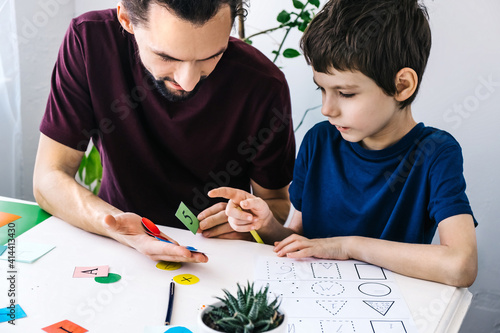 Autism awareness concept. Autism schoolboy during therapy at home with his tutor with learning and having fun together.