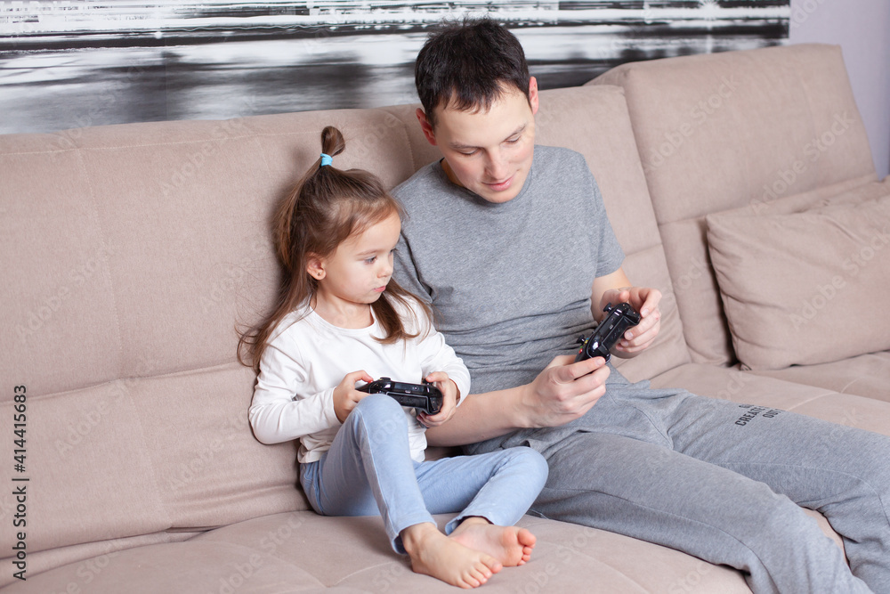 Dad teaches his daughter to play video games. Gamers. Generation. Happiness. Family Dad teaches his daughter to play video games. Gamers. Generation. Happiness. Family