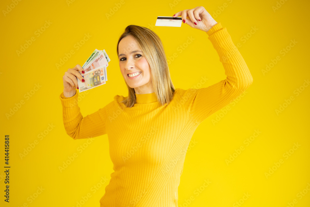 Portrait of an excited young woman holding money banknotes isolated over yellow background Portrait of an excited young woman holding money banknotes isolated over yellow background