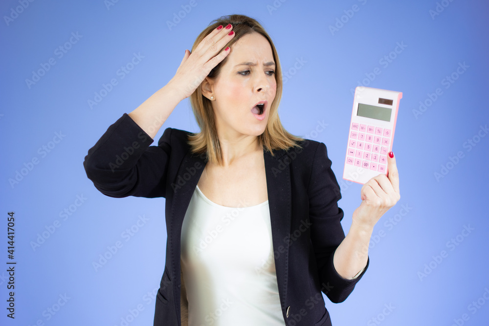 Young business woman holding calculator with surprised gesture