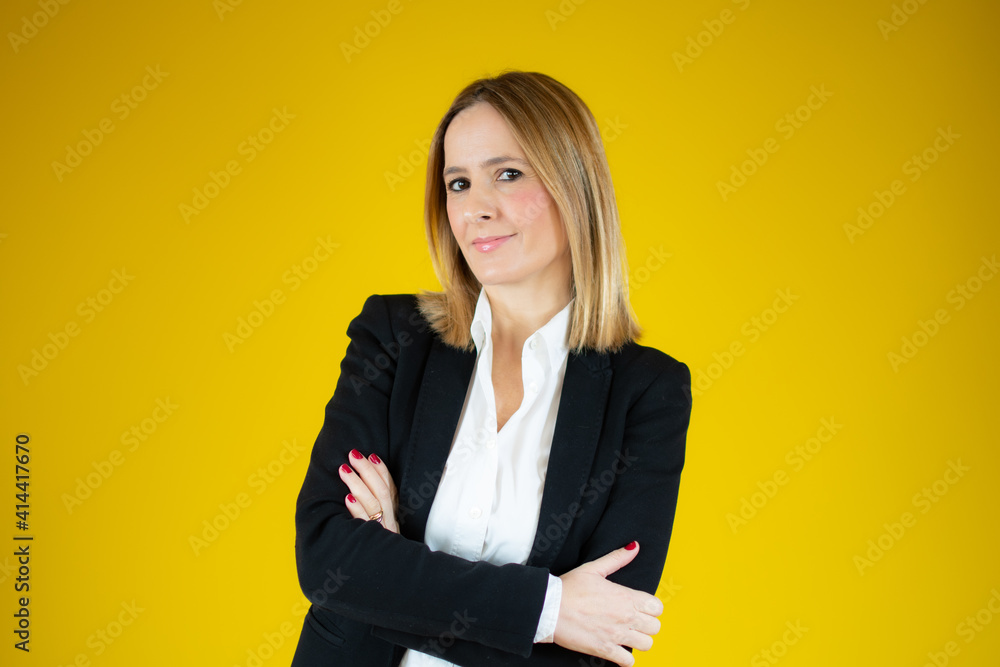 Young beautiful business woman with arms folded over yellow background. Young beautiful business woman with arms folded over yellow background.