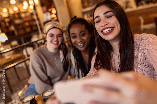 Three young multi ethnic women enjoy coffee at a coffee shop. © Zoran Zeremski