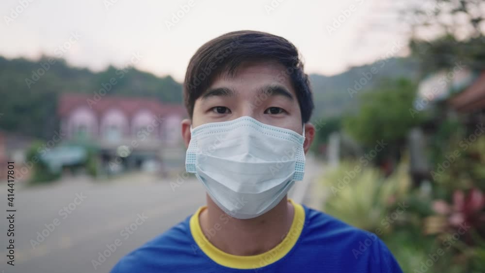 Asian young man feel confident and safe wearing protective medical face mask standing on urban road sidewalk, pandemic, social distancing new normal lifestyle, stay safe, virus covid19 prevention Asian young man feel confident and safe wearing protective medical face mask standing on urban road sidewalk, pandemic, social distancing new normal lifestyle, stay safe, virus covid19 prevention