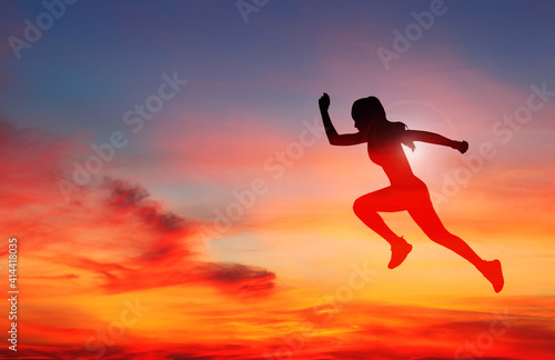 Woman runner in silhouette on colour sky background. Dynamic movement. Side view