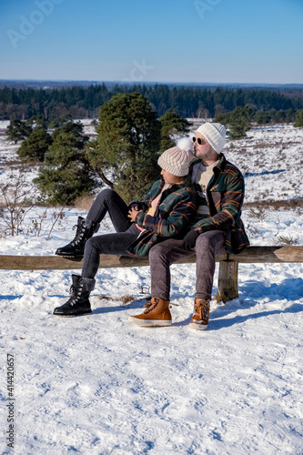 couple man and woman mid age walking in the snow, snow covered hills of the Sallandse Heuvelrug, Landscapes of the Holterberg near Holten, The Netherlands. Winter in the Netherlands photo