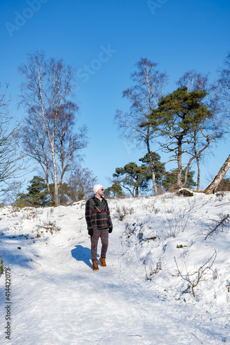 man mid age walking in the snow, snow covered hills of the Sallandse Heuvelrug, Landscapes of the Holterberg near Holten, The Netherlands. Winter in the Netherlands photo