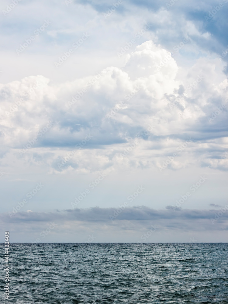 Cloudy sky over the horizon in the ocean. Vertical seascape background