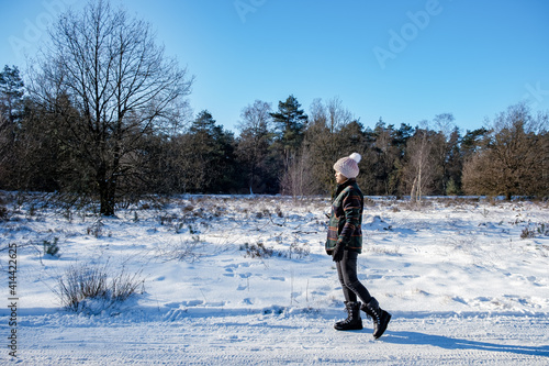  woman mid age walking in the snow, snow covered hills of the Sallandse Heuvelrug, Landscapes of the Holterberg near Holten, The Netherlands. Winter in the Netherlands photo