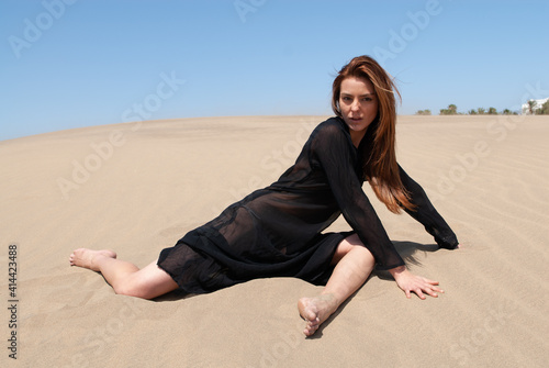 Muslim woman in a black robe in the desert dunes
