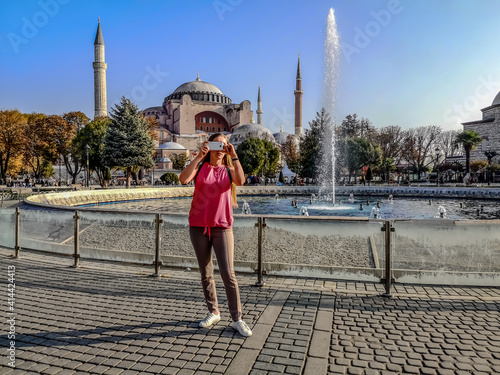 Canvas Print Young woman tourist with a smartphone in her hands near the fountain on the background of Hagia Sophia in Istanbul (Turkey)