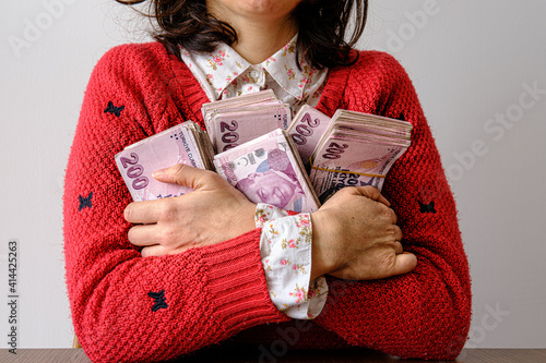 Fotografija Young woman hugging piles of banknotes