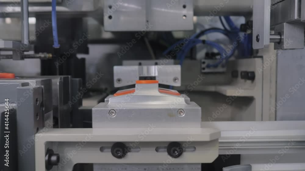 Production line of automatic blow molding machine - forming empty orange plastic jerrycans on conveyor belt with hydraulic punch- close up. Manufacturing, industry, technology equipment concept Production line of automatic blow molding machine - forming empty orange plastic jerrycans on conveyor belt with hydraulic punch- close up. Manufacturing, industry, technology equipment concept