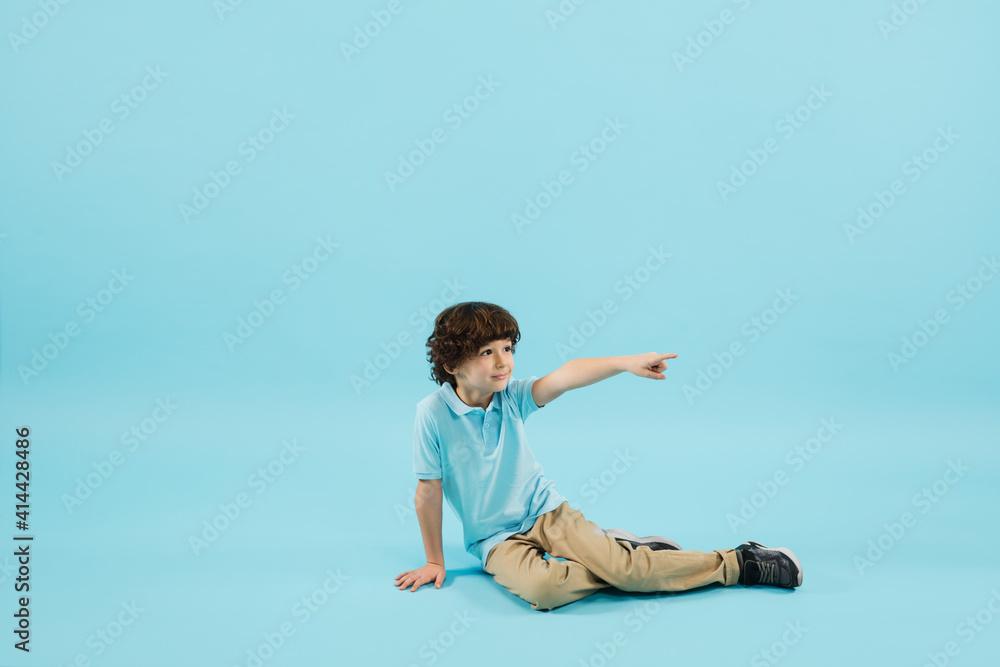 Pointing out, showing. Childhood and dream about big and famous future. Pretty little boy isolated on blue studio background. Dreams, imagination, education, facial expression, emotions concept. Pointing out, showing. Childhood and dream about big and famous future. Pretty little boy isolated on blue studio background. Dreams, imagination, education, facial expression, emotions concept.