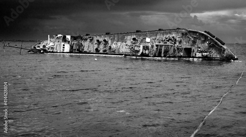 Fotografie sunk wreck ship on the coastline in black and white