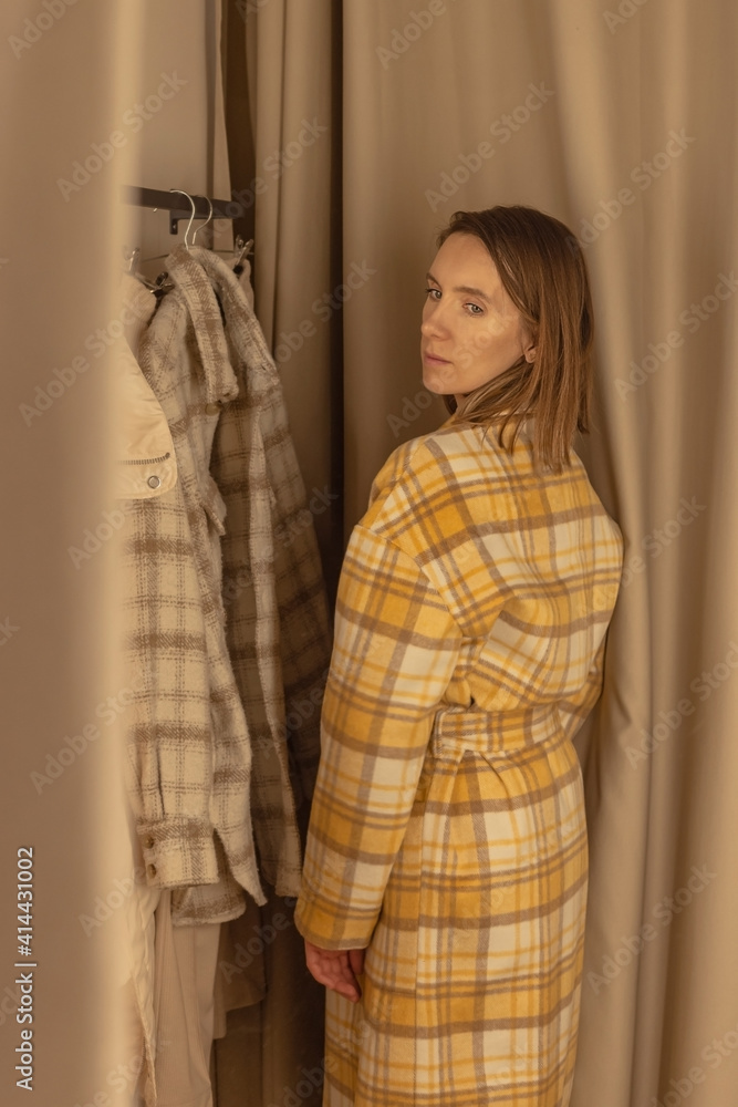 Fototapeta premium Woman trying on a coat in a fitting room of a clothing store